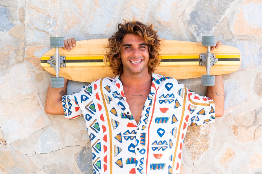 Young caucasian man practicing skateboarding on the beach