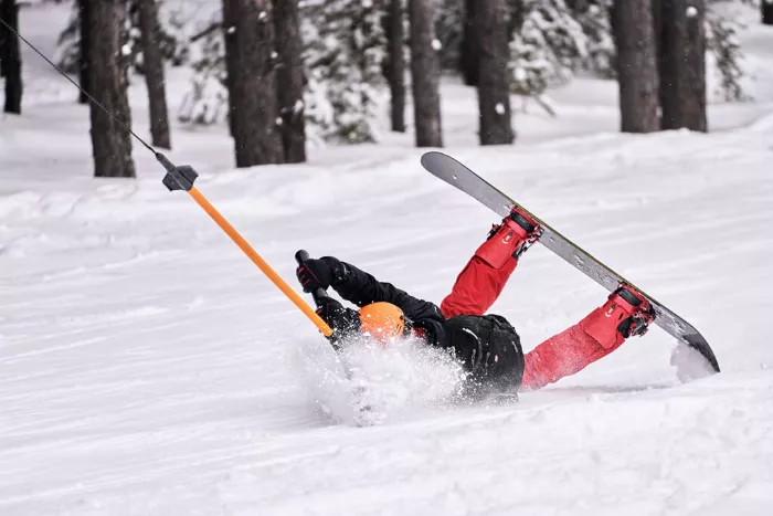 A beginner snowboarder struggling with the drag lift