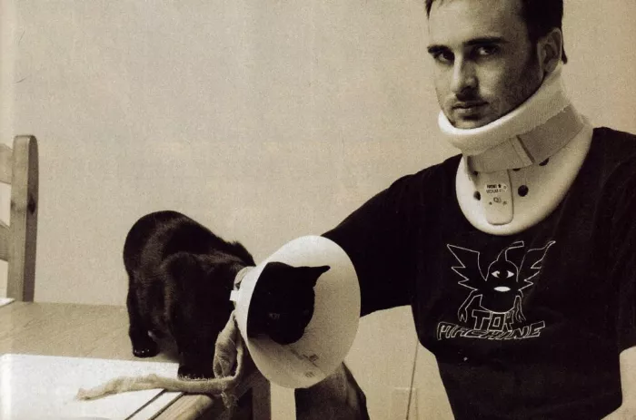 A black and white photo of Ed Templeton wearing a neck brace after a serious fall, highlighting the serious consequences of skating-related injuries.