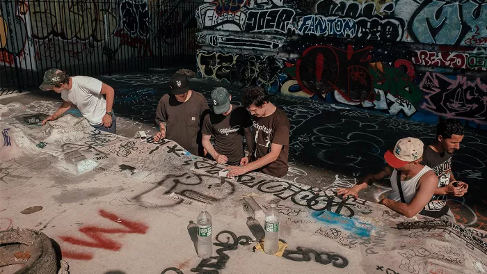 A close-up of a fingerboarder performing a trick on a small concrete ramp.