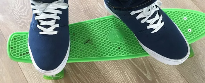 A close-up of a green Penny board, showing the waffle-grip pattern and the texture of the plastic deck