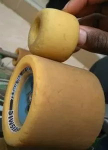 A close-up of a longboard wheel, highlighting its size and urethane material