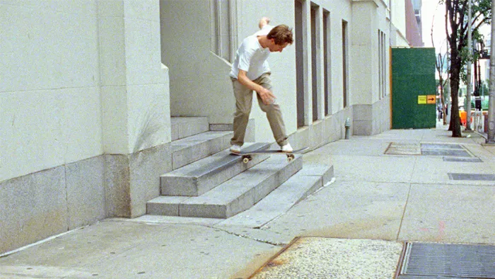 A close-up of Mark Suciu's skateboard in action, highlighting the raw texture of the surface