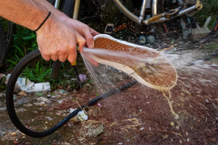 A close-up of the Vans Slip-On Pro skate shoe being cleaned with a hose, with the poop remaining stuck in the waffle pattern.