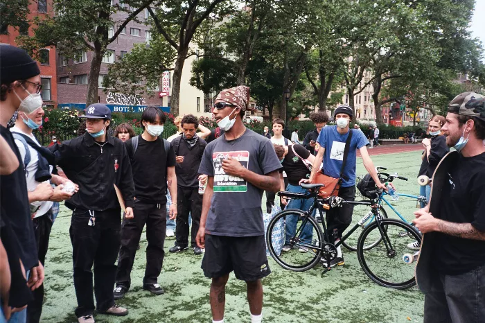 A group of people march down a city street, many holding signs, with some wearing masks.