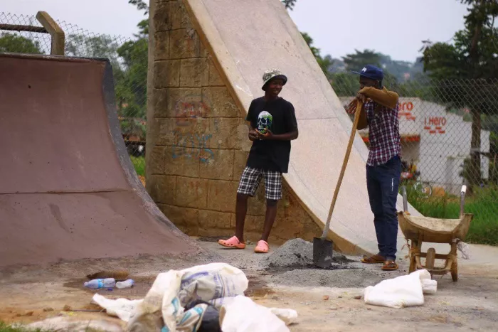 A group of skateboarders are skating at a concrete skatepark in Uganda