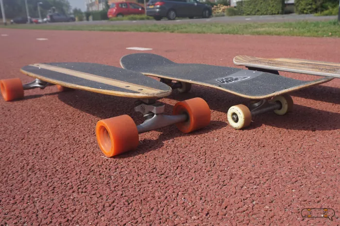 A longboard positioned next to a skateboard, highlighting the size difference between the two.