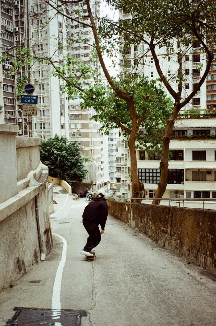 A low-angle shot of skateboarders riding through a gritty street in Hong Kong