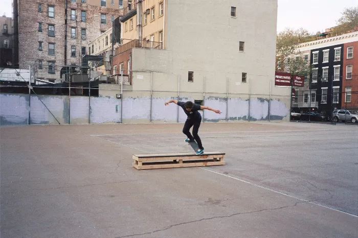 A makeshift skate box constructed from wooden boards and other materials, situated on a grassy area.