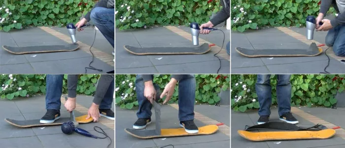 A person using a hair dryer to heat up and peel off old grip tape from a skateboard