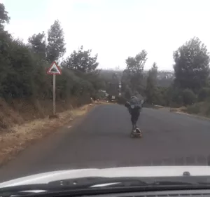 A road sign for a steep hill with a skater in the background