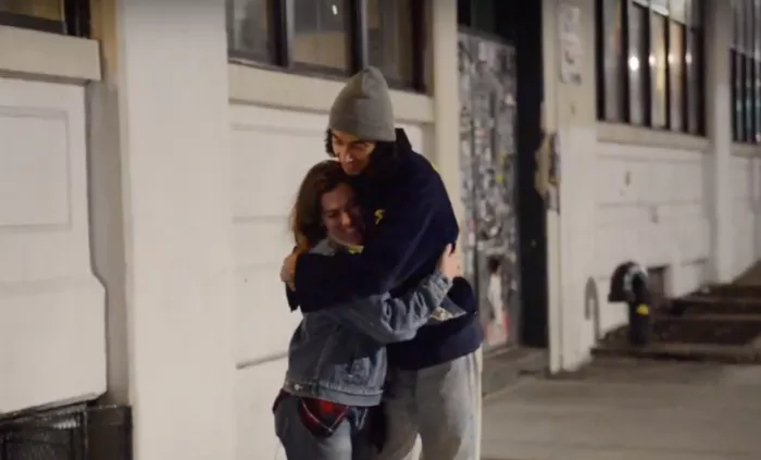 A shot of the two contestants, a skateboarder and a non-skater, sitting together on a bench during their date