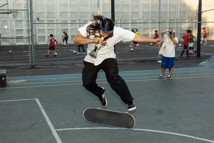 A side view of a skater doing a tre flip at the challenge