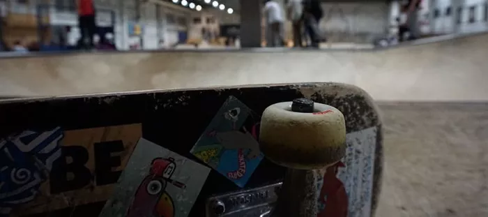 A skateboard resting on the concrete in a skatepark, emphasizing the accessibility of the sport.