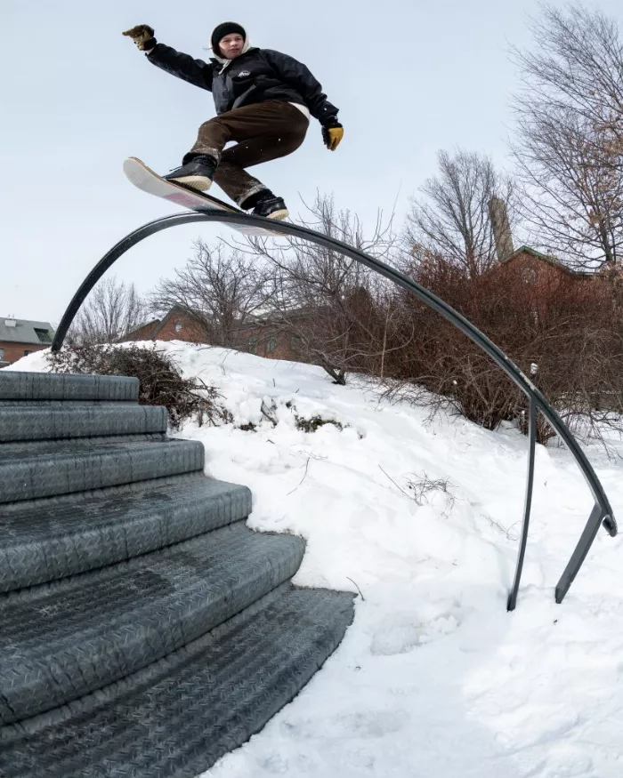 A snowskater performing a boardslide