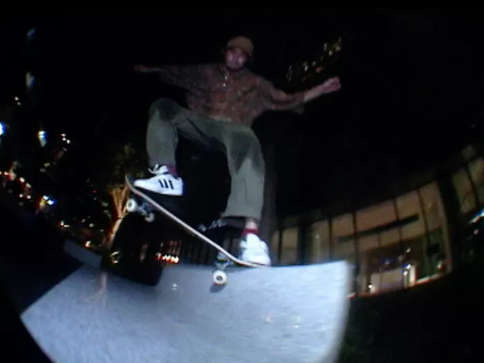 A still image from the &quot;Pale&quot; skateboarding video, showing a skateboarder performing a trick in a dimly lit, urban environment.