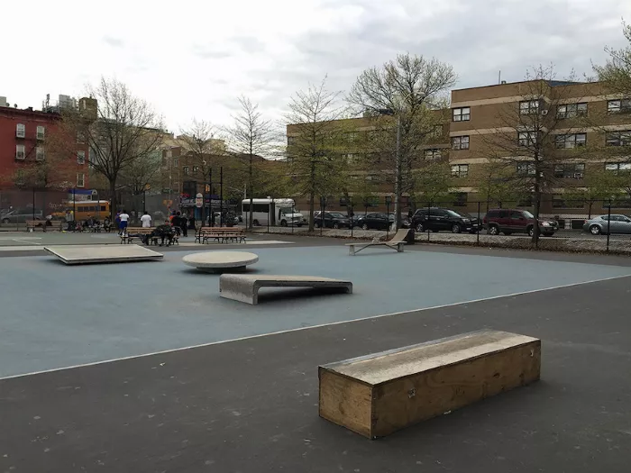 A wide shot of Blue Park, showcasing the blue concrete surface and surrounding buildings.