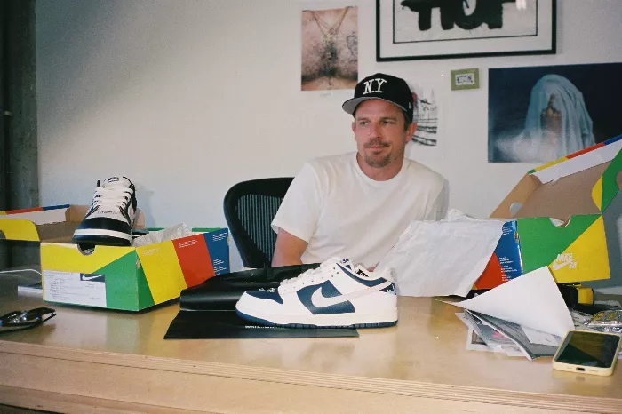 An unidentified man sitting at a desk looking at shoes