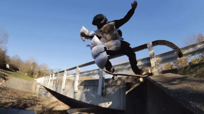 Andy Schrock tail dropping into a lake with helmet and pillows