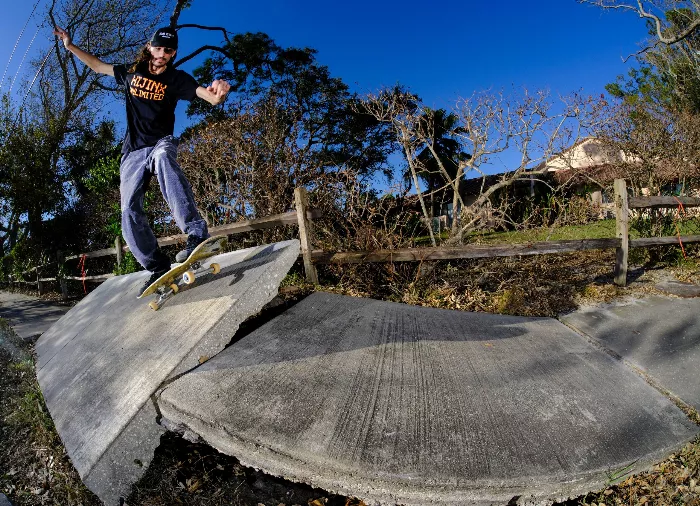 Cameron Klima performs a kickflip manual on a longboard. The photo shows the skater in motion, with his board slightly angled.