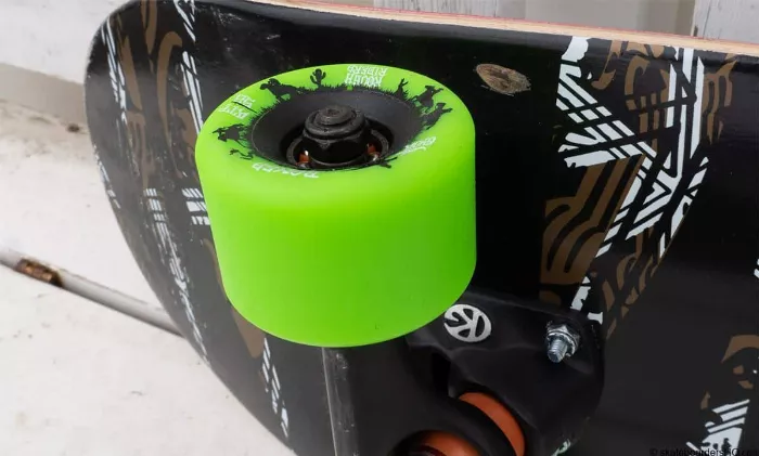 Close up of a custom cruiser trick setup, showing black trucks and deck, neon green wheels and silver bearings