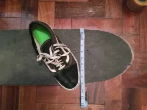 Close-up of a foot on a longboard, showing the heel and toe reaching the edges