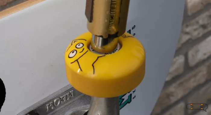 Close-up of a hand adjusting axle nuts on a longboard wheel