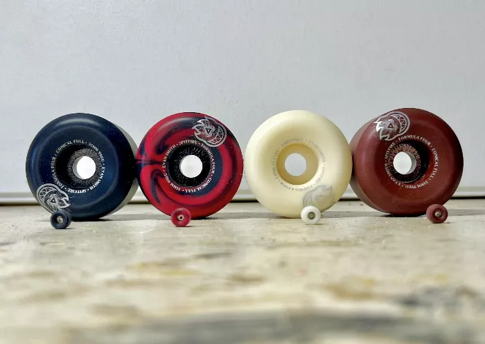 Close-up of a person's hand holding several miniature skateboard wheels, showcasing their small size and detailed construction.