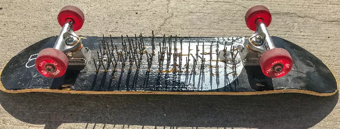 Close up of a skateboard with nails hammered through it