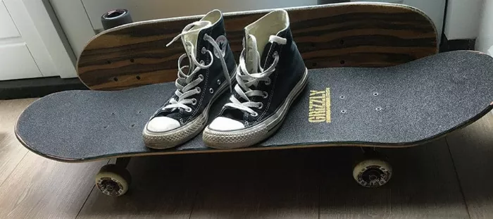 Close-up of Converse shoes on a skateboard deck