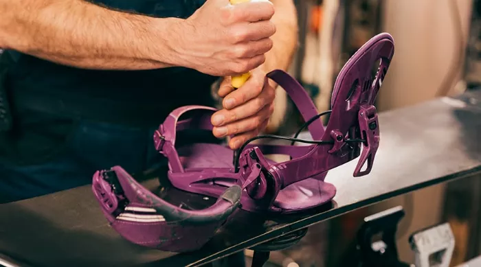 Close-up of worn snowboard bindings, highlighting the wear on straps and baseplate