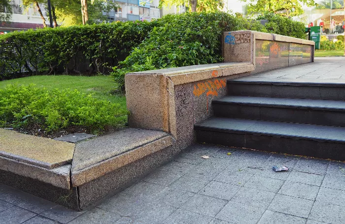 Duncan McDuie-Ra, a professor of Urban Sociology and a skateboarder, stands in an urban environment, with a skateboard under his arm.