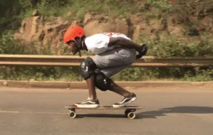 Longboard rider in a tuck position demonstrating topmount deck