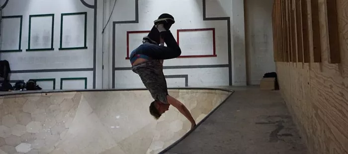 Longboarder doing a handplant in a bowl