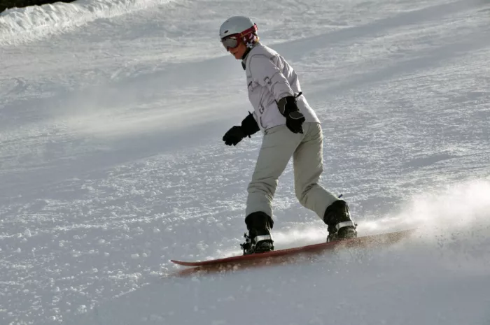 Older adult learning to snowboard on a gentle slope