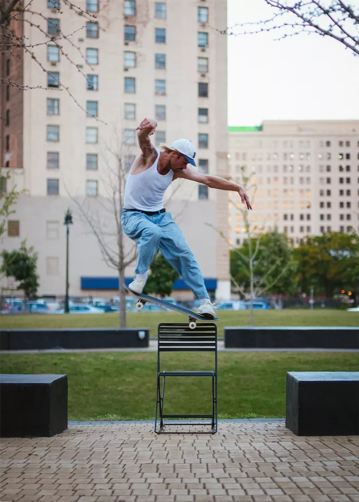 Ryan Townley performing a trick on a skate spot with a chair in the background