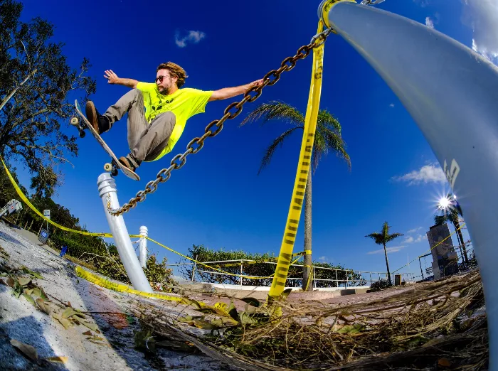 Ryan Ward performs a pole jam on a longboard, the photo has a vintage feel, with the skater in motion against a muted background.