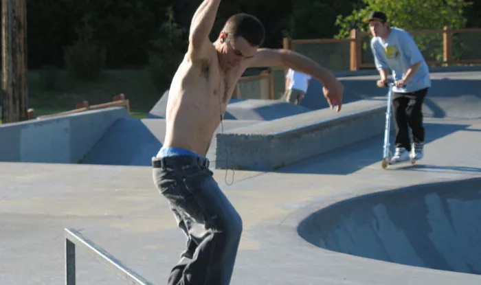 Shirtless skater wearing headphones at a skatepark