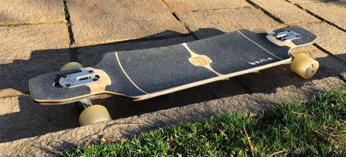 Skateboarder on a Bustin Maestro longboard riding on rough pavement