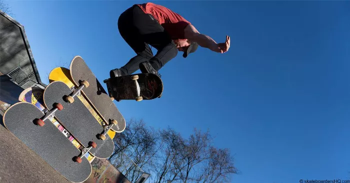 Skateboarder performing an ollie over multiple decks