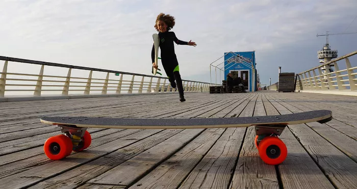 surfer kid and a skateboard on a pier