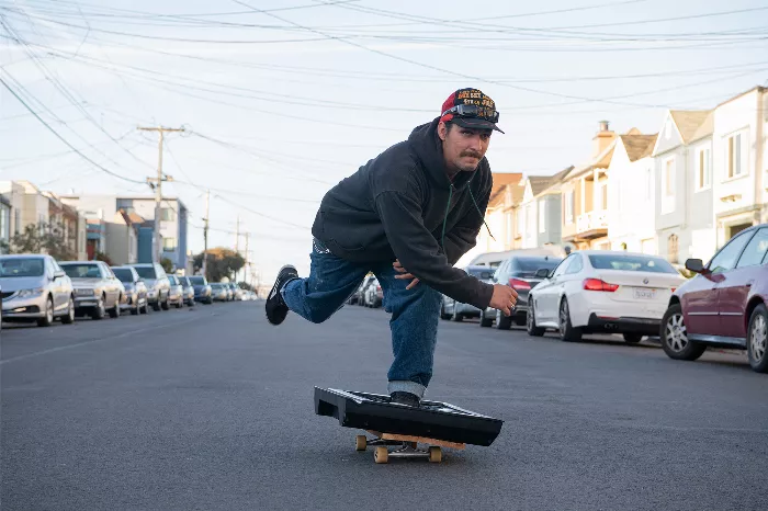 Tanner Napper, a skateboarding stuntman, is captured here riding a TV down a steep hill, showcasing his unique approach to skateboarding and stunts