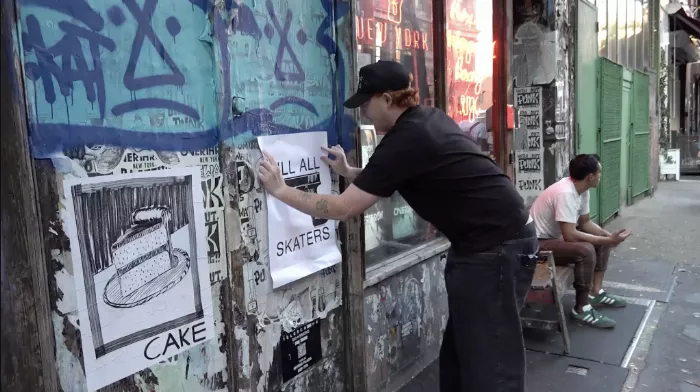 Timothy applying wheatpaste to a wall in preparation for a poster