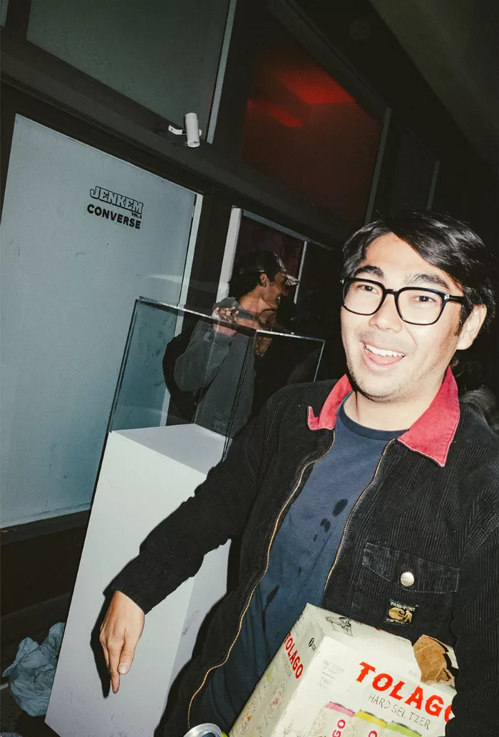 Videographer Ryan Lee next to a plinth stacked with books